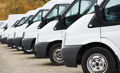 A row of white vans parked next to each other, potentially indicating an accident involving company vehicles.