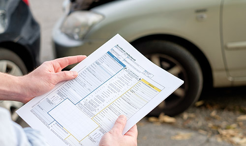 a person holding a police report at a car accident
