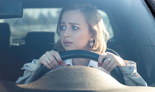 blonde woman with an concerned expression tensely driving, experiencing vehophobia